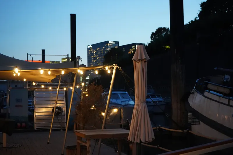 Deck des Harbor Club am Abend mit Lichterketten, im Hintergrund der Medienhafen