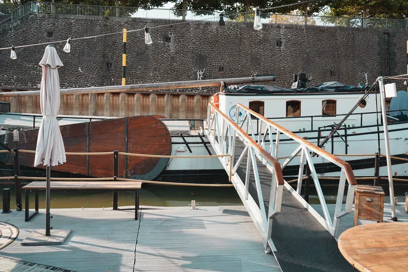 Gangway vom Steg zum Schiff, davor Sitzbank und Sonnenschirm