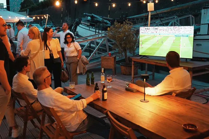 Gäste verfolgen ein Fußballspiel auf einem großen Bildschirm im Harbor Club
