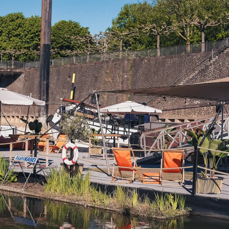 Lounge-Bereich mit orangefarbenen Liegestühlen auf dem Steg des Harbor Club