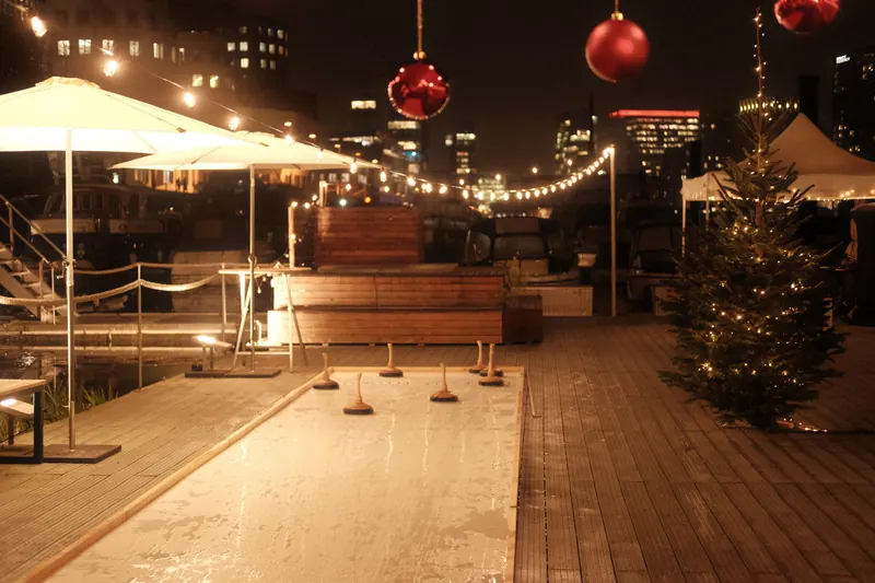 Weihnachtlich geschmückter Harbor Club am Abend mit Eisstockbahn