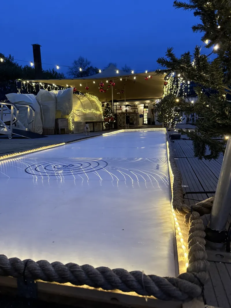 Beleuchtete Eisstockbahn im Winter Club zur blauen Stunde